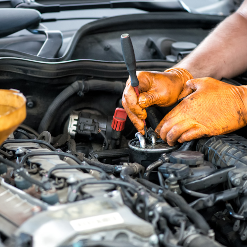 A mechanic working underneath a car hood.